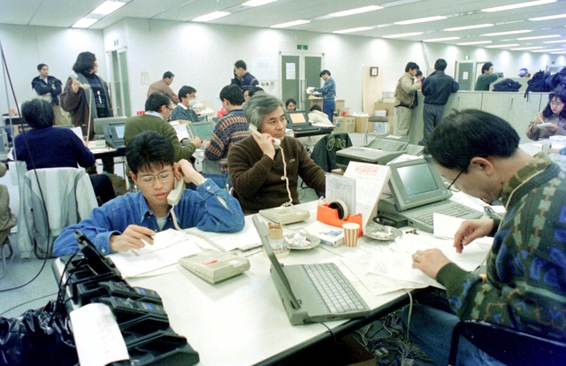 本社ビルが全壊し、移転した編集局で電話取材する記者や編集作業にあたるデスク＝１９９５年１月２７日、神戸市中央区東川崎町１