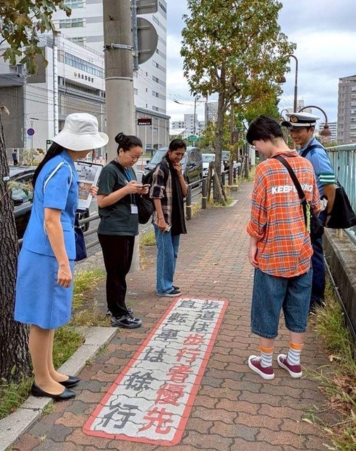 兵庫署員から歩道での歩行者優先について説明を受ける外国人ら＝神戸市内（兵庫署提供）