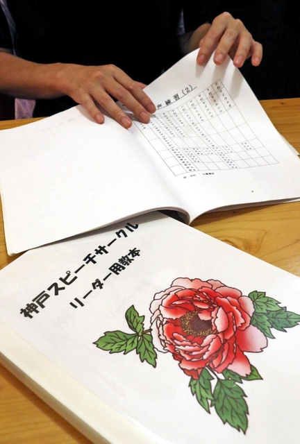 話し方教室の教本を手に体験を語るシンジさん＝神戸市内