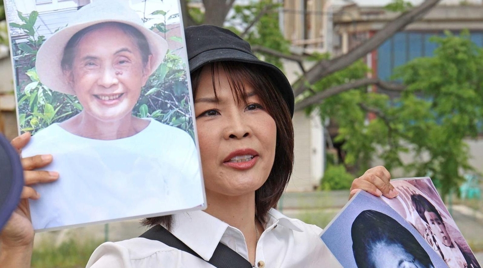 戦跡ウオークでガイドをする馬場敦子さん。右手に持つのは母の故・中田政子さん、左は祖母の三木谷君子さんと伯母の弘子さんの写真＝６月１日、神戸市兵庫区の大輪田橋