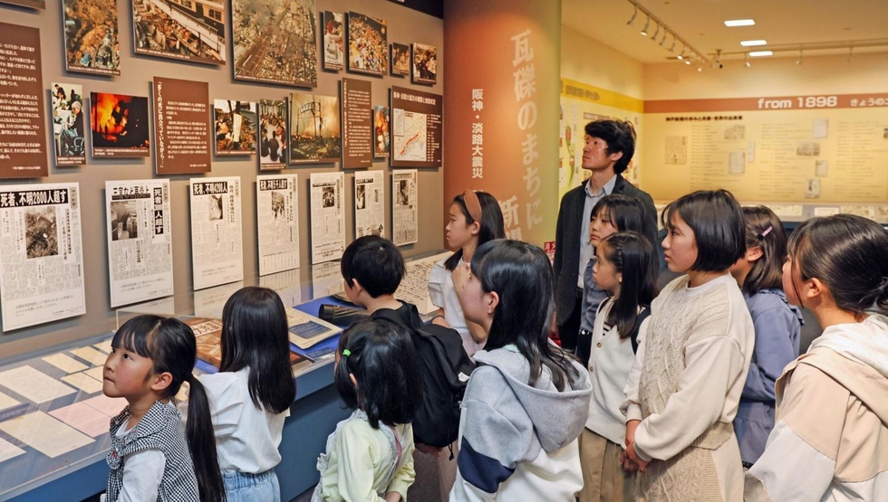 阪神・淡路大震災の記録や当時の写真を見る子どもたち＝４月６日、神戸新聞報道展示室「ニュースポート」