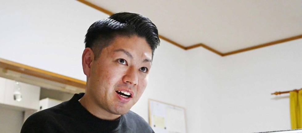 アルバムをめくり、亡くなった両親への思いを語る前田健太さん＝滋賀県草津市（撮影・斎藤雅志）