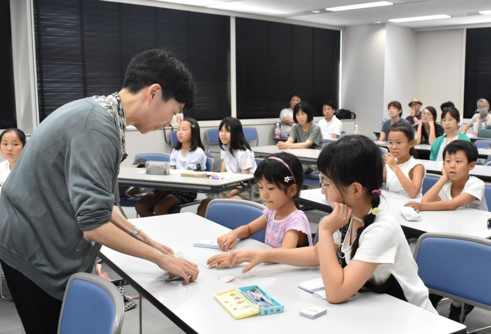 岸本くるみさん（左）と接する子どもたち＝８月３日、神戸新聞社