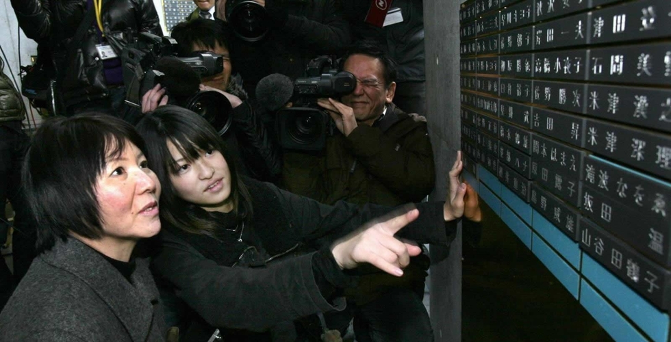 父の名が刻まれた銘板を見つめる小島汀さん（左から２人目）＝２００９年１２月、神戸市中央区加納町６