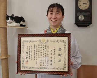 感謝状を受けた上月香織さんと、女性を慰めた看板猫の「宇治ちゃん」＝神戸市灘区城内通３