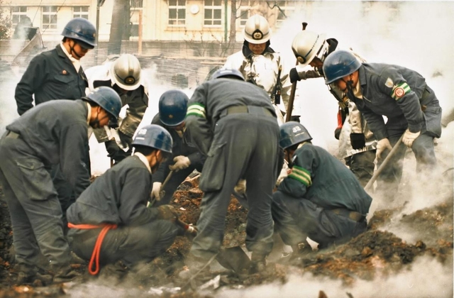 くすぶる焼け跡で行方不明者を捜索する警察官や消防士＝１９９５年１月１９日、神戸市長田区