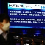 ２月２日に緊急事態宣言の延長決定のニュースを伝える大型ビジョン前を歩くマスク姿の男性