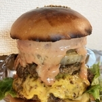 肉厚なパティの間からチーズがあふれ出すハンバーガー（提供）