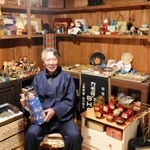 改装した蔵で古いポットを持つ畑光さん。古道具などがずらりと並ぶ＝三田市三田町