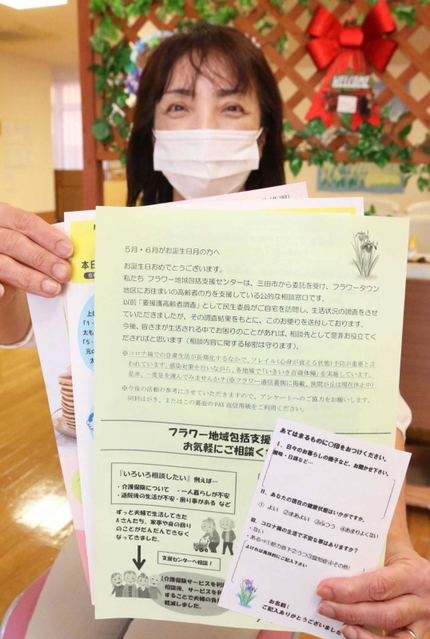 高齢者に送るメッセージや案内を手にする職員の藤原さゆりさん＝フラワー地域包括支援センター