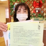 高齢者に送るメッセージや案内を手にする職員の藤原さゆりさん＝フラワー地域包括支援センター