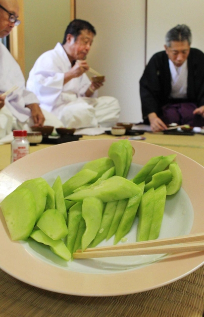 神事の後でキュウリを食す氏子ら＝三田市下田中