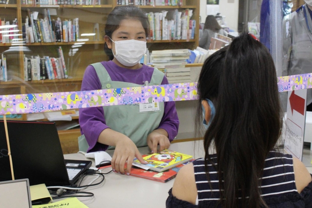 カウンターで返却期限を伝えて本を貸し出す＝三田市立図書館