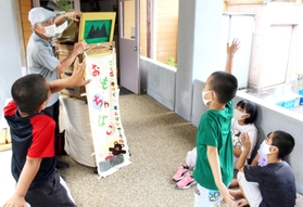 大きく手を上げてクイズに答える子どもたち＝母子小学校