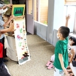 大きく手を上げてクイズに答える子どもたち＝母子小学校