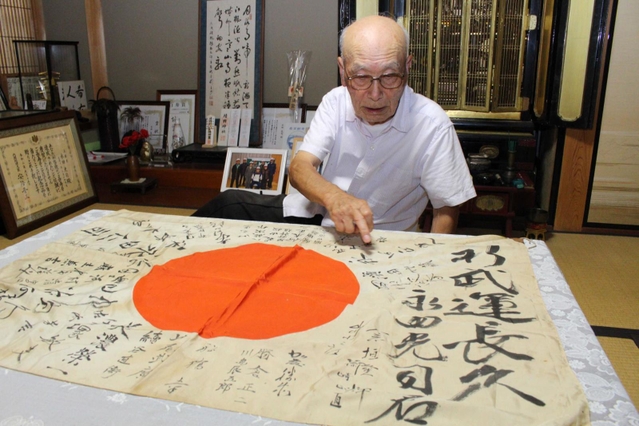 出征前にもらった寄せ書きを見ながら話す永田さん＝三田市