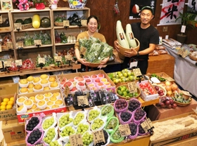 「にじ屋Ｓａｎｄａ　ｂａｓｅ」を開いた片山慶彦さん（右）。所狭しと青果が並ぶ＝三田市西山２の８の１９