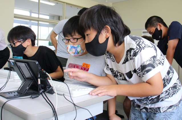 教え合いながらゲームを作る児童＝志手原小学校