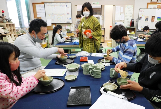 自作の茶わんで抹茶をたてる親子連れら＝三田市、三輪明神窯史跡園