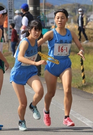 女子・北摂三田の１区児玉七海主将（右）からたすきを受け取る２区上崎柊侑選手＝丹波篠山市内（撮影・吉田敦史）