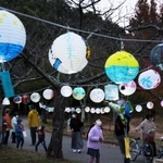 色とりどりのちょうちんを見上げる親子連れら＝三田谷公園