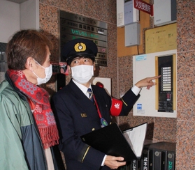 各階の火災発生を知らせる受信盤について説明する消防隊員（右）＝三田市中央町