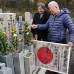 杉尾五郎さんの日章旗を墓前に供える甥の典一さん（右）と三田市遺族会の竹内ハルミさん＝三田市東野上