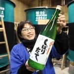 蔵の中で新酒を持つ岡村理恵さん＝岡村酒造場