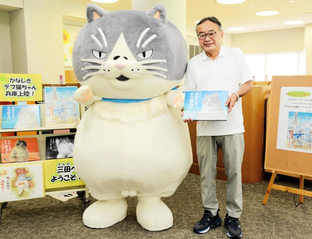 三田市立図書館ウッディタウン分館を訪れ、東和久館長（右）に絵本を手渡すマル＝三田市けやき台１