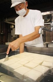 厚揚げにする豆腐を切り分けていく＝三田市大川瀬