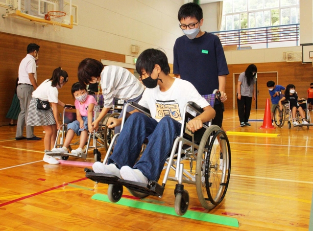 児童は車いすに乗る怖さや押す大変さを体験した＝高平小学校