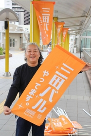 三田バル参加店が掲げる旗を持つ梅沢委員長＝三田市駅前町