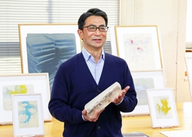 制作に使う石灰石を手にリトグラフの魅力を語る安井良尚さん＝三田市四ツ辻