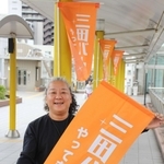 三田バル参加店が掲げる旗を持つ梅沢委員長＝三田市駅前町