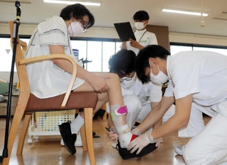 河合さんの装具を調節する学生ら＝三田市福島