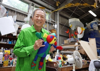 アトリエでサンダリーノの人形を持つ新宮晋さん