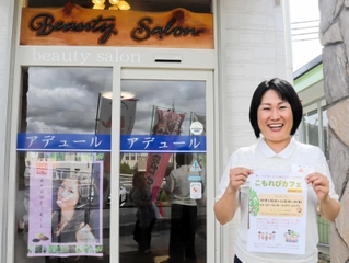 美容院の前でこもれびカフェのチラシを手にする木戸典子さん＝三田市弥生が丘５