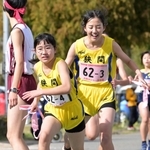 女子・狭間の３区福井沙和選手（右）からたすきを受け取る４区仲井鈴音選手＝豊岡市日高町（撮影・斎藤雅志）