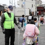 見守り活動最終日。児童にあいさつする志儀好文さん（左）＝三田市屋敷町