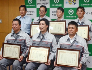 大西孝男消防長（後列左端）から感謝状を受け取った「日立Ａｓｔｅｍｏ阪神」の社員＝三田市消防本部