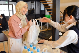 ＮＰＯ法人のスタッフから食料や日用品を受け取る市内在住の外国人＝三田市三田町、三田ほんまち交流館「縁」