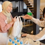 ＮＰＯ法人のスタッフから食料や日用品を受け取る市内在住の外国人＝三田市三田町、三田ほんまち交流館「縁」