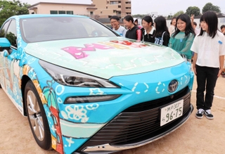 「ＭＩＲＡＩ」にラッピングされた自作のデザインをクラスメートに紹介する遠藤寧々さん（右端）＝三田小学校