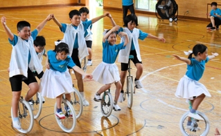 笑顔で一輪車演技を披露する児童たち＝母子小学校