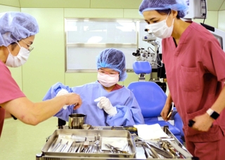 手術室に入り、医療器具について説明を受ける安田瑞葉さん（中央）と母の敦子さん（右）＝三田市天神１