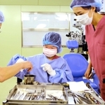 手術室に入り、医療器具について説明を受ける安田瑞葉さん（中央）と母の敦子さん（右）＝三田市天神１