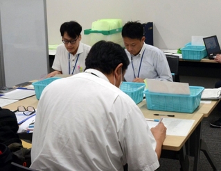市選管の職員（奥）が立候補に必要な書類を点検した予備審査＝三田市役所