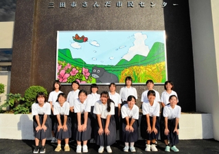 さんだ市民センターの玄関を飾る大作を描いた八景中学美術部の生徒たち＝三田市三田町