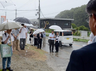 雨の中、候補者の第一声に耳を傾ける支援者ら＝三田市内