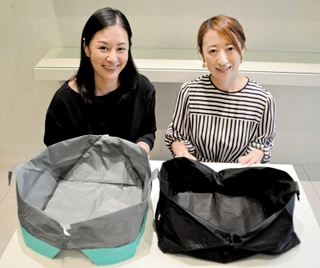 自立するエコバッグ「オリバ」の新モデル（手前左）を開発した山口知夏代表（左）と熊澤恭子執行役員。右の商品は旧型のＬサイズ＝芦屋市川西町